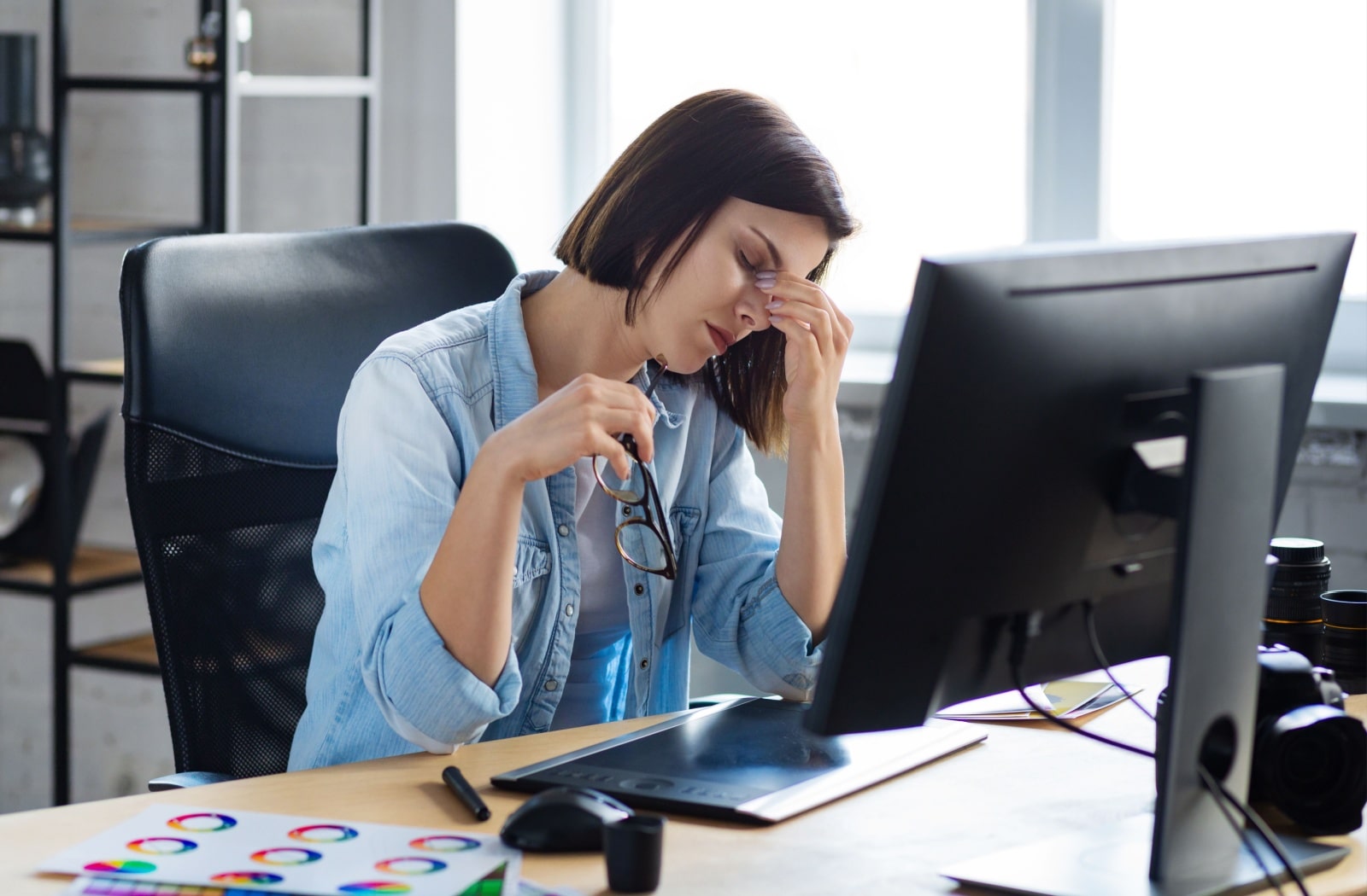 A woman experiencing eye strain after working for an extended amount of time in front of a computer monitor.