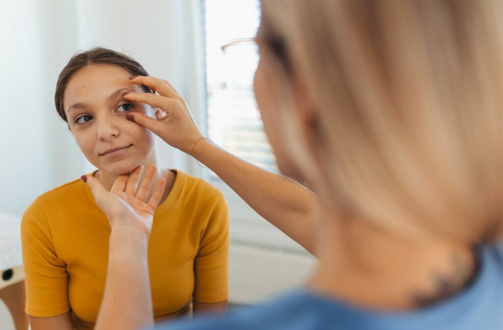 Eye care professional examining a person's eye in a bright medical office setting