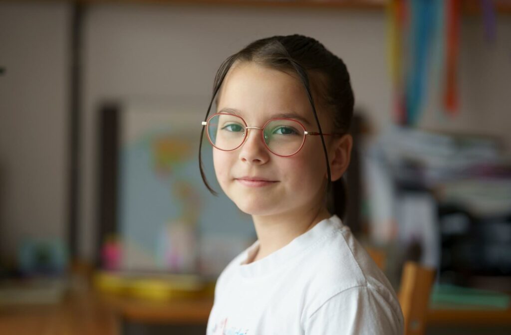 Smiling child wearing red glasses indoors