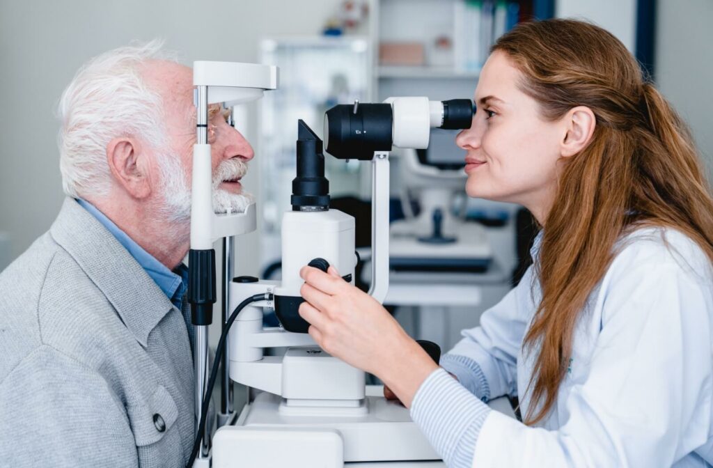 An optometrist examines an older adult's eyes using a slit lamp during a routine eye exam.